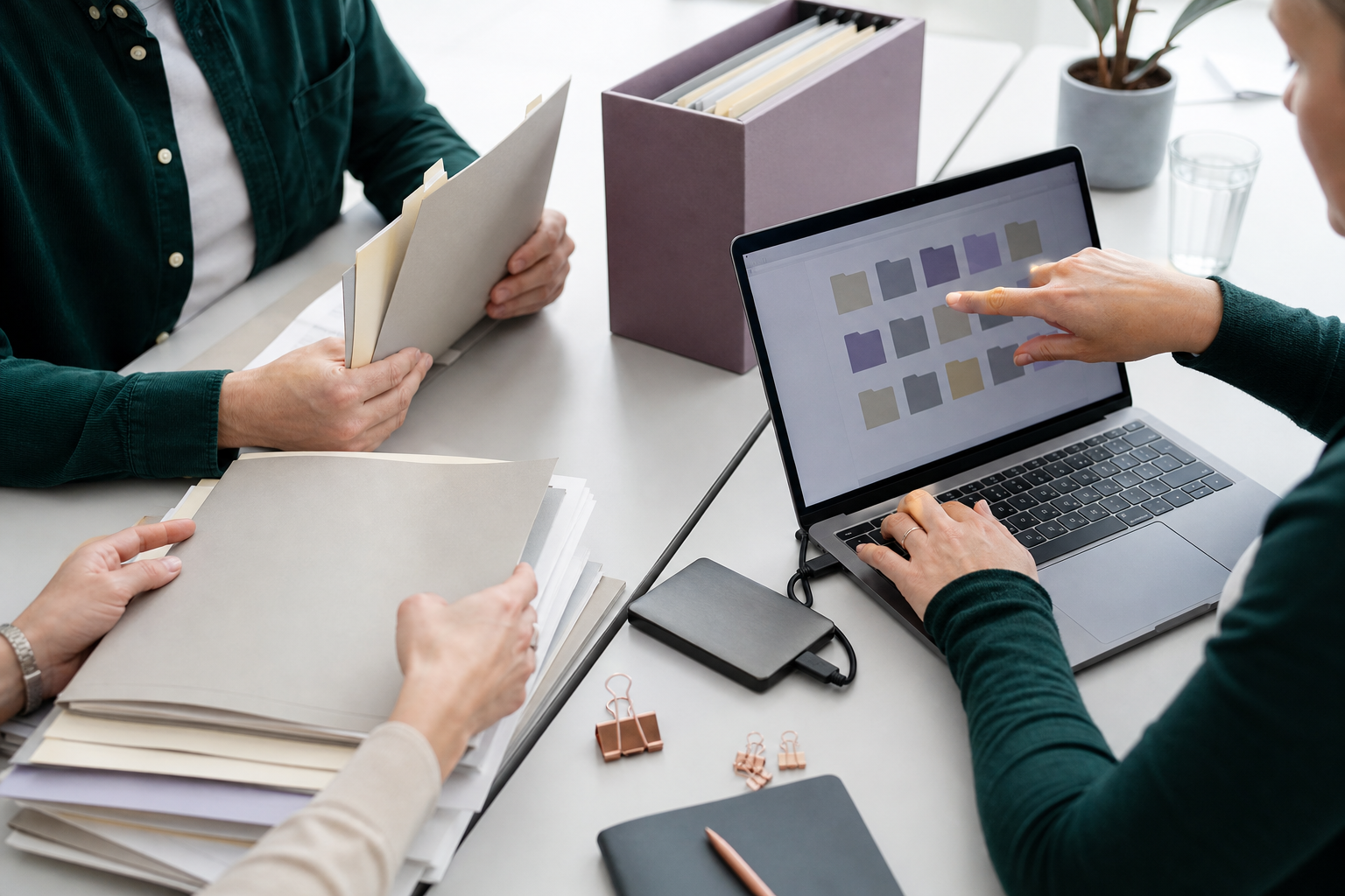 Collega’s ordenen mappen en bestanden op papier en op een laptop